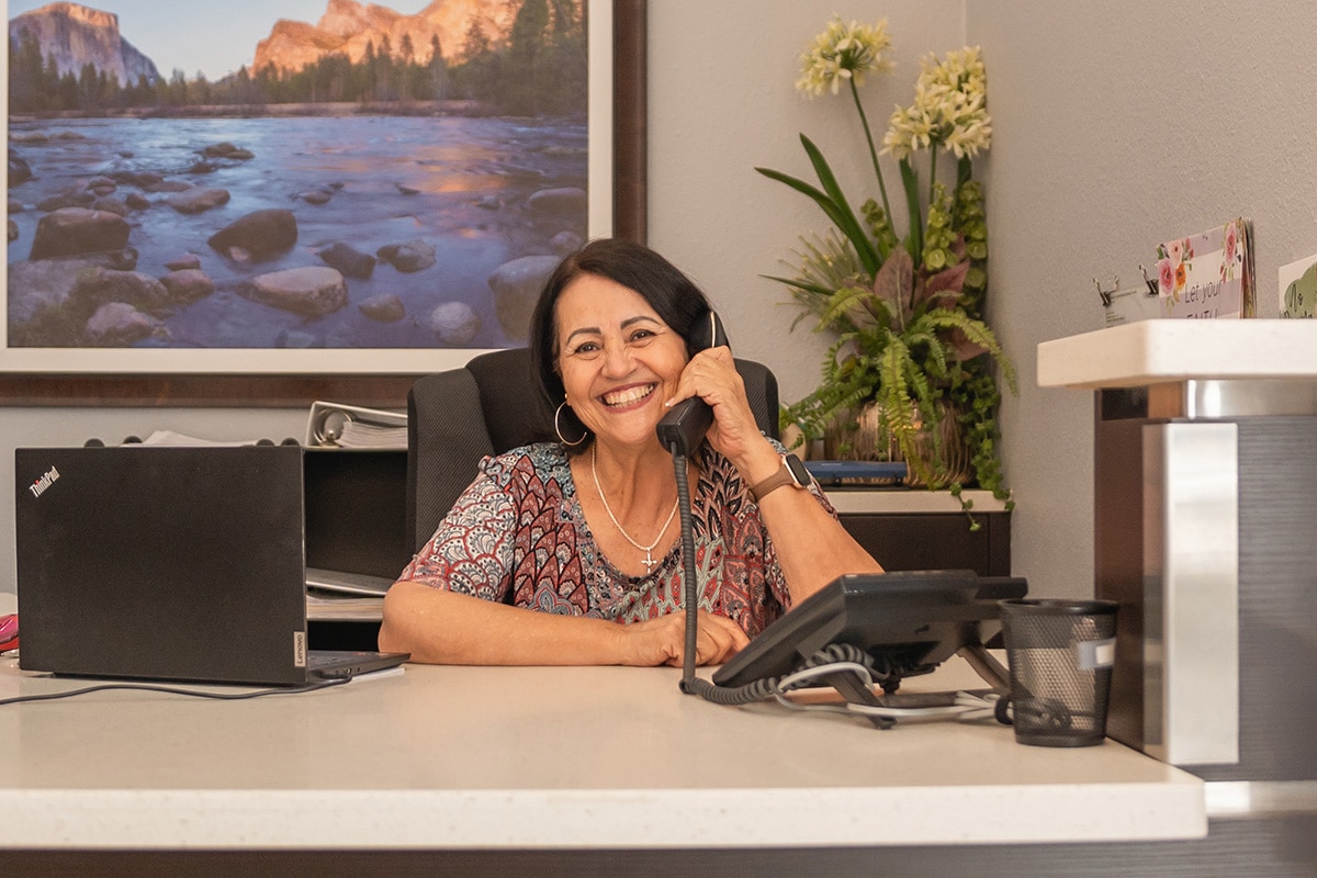 a receptionist smiling and on the phone at the front desk at Gateway