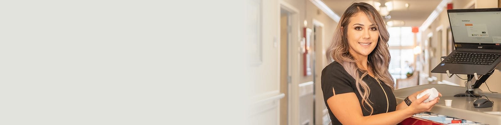 A nurse standing in the hallway next to a nurse's cart